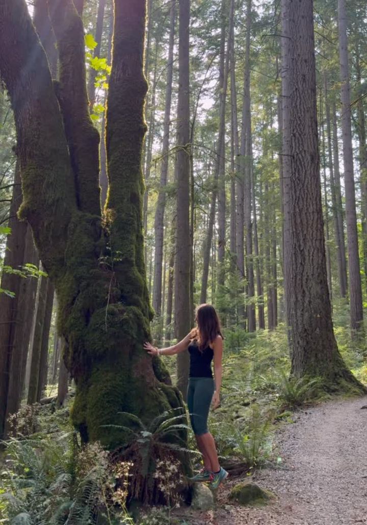 Monika touching a moss-covered maple in a cedar forest